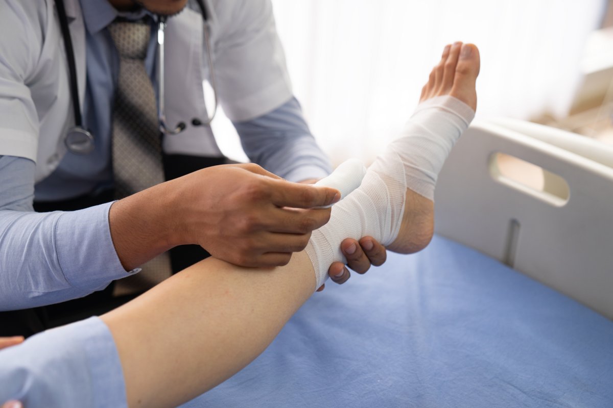 doctor bandaging wound on patient's foot