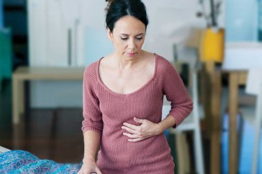 Woman holding her stomach with pained expression